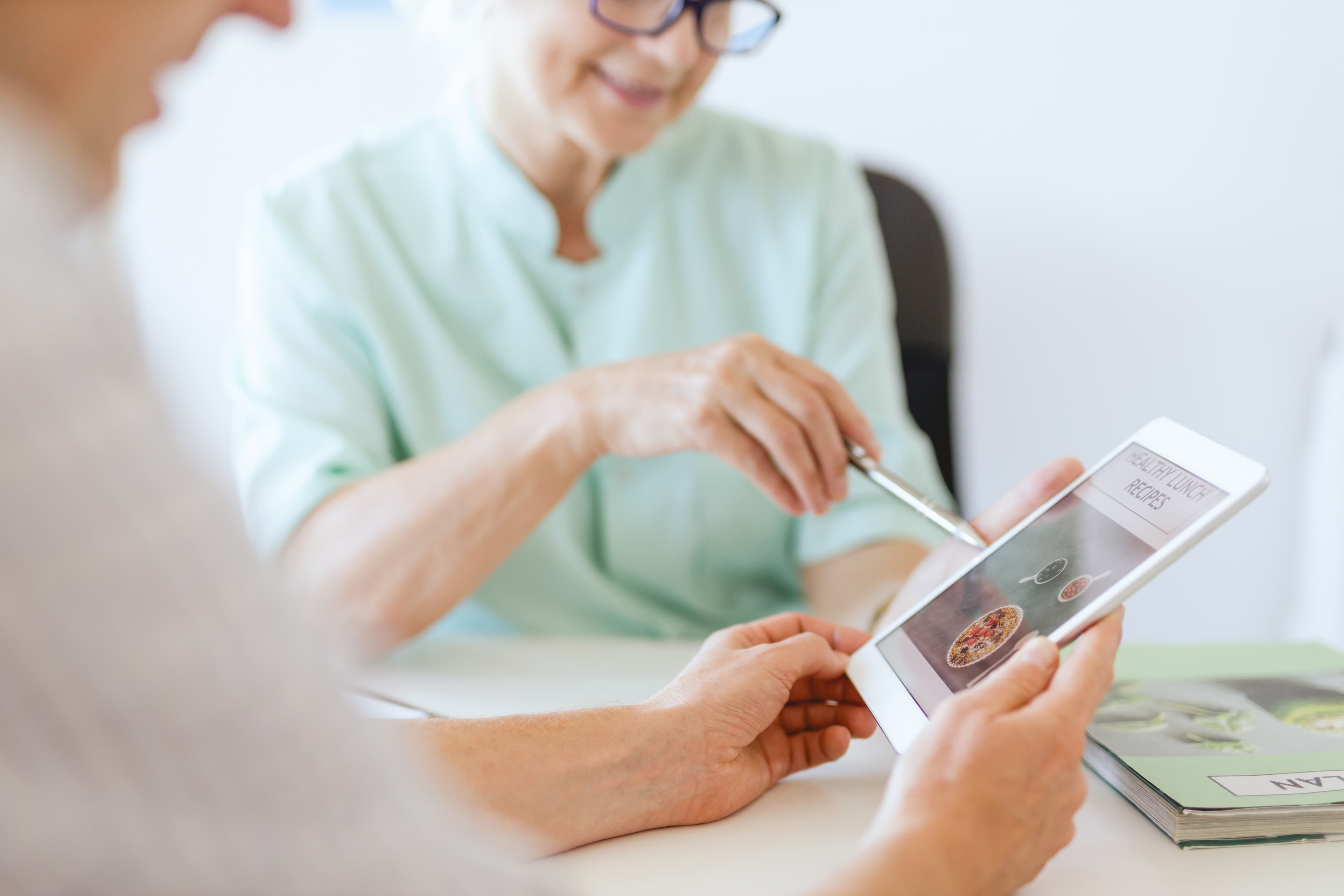 Nutrition consultation with a practitioner discussing meal ideas on a tablet