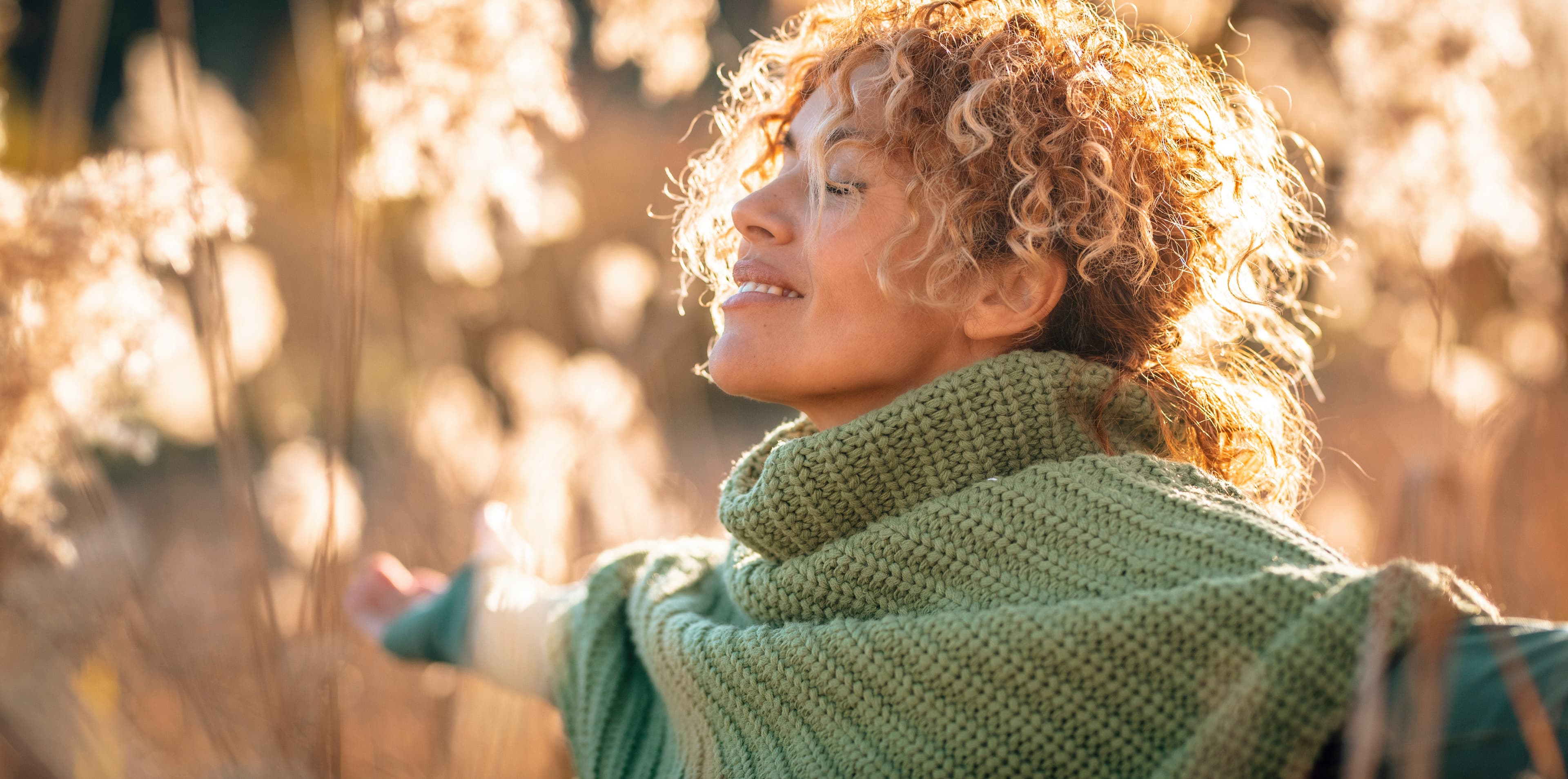 Woman wearing a green scarf enjoying the sunlight outdoors