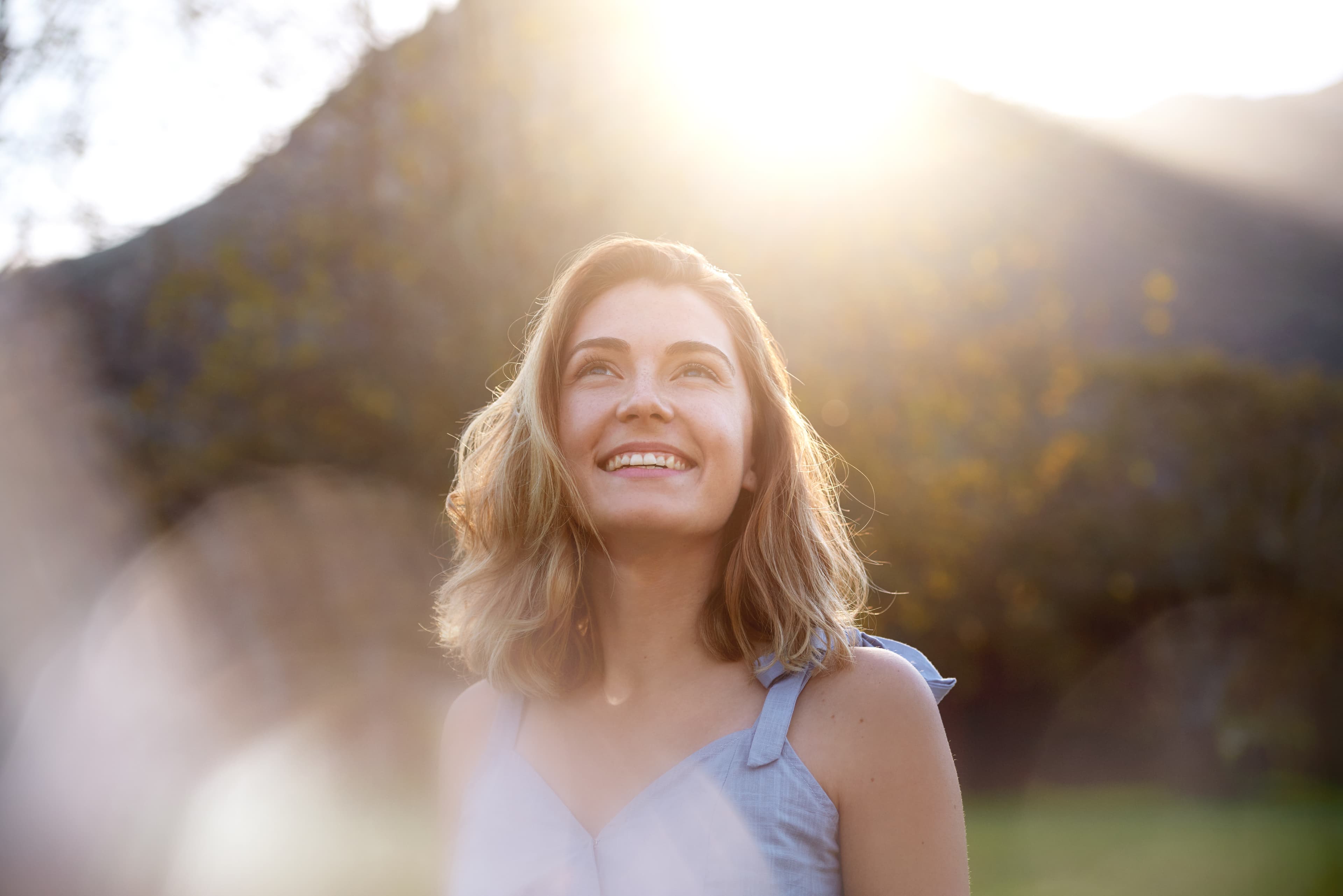 Woman smiling outdoors in warm sunlight